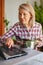 Cooking woman looking at computer while preparing food in kitchen. Beautiful mature woman reading cooking recipe