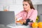 Cooking woman looking at laptop while preparing food in kitchen