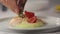 Cooks hand holds a late with piece of red fish salmon with potato puree and decorated with thyme