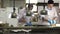 Cooks making dishes on the kitchen near distribution desk with lamps.