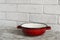 Cookware - red with white dots enameled bowl on bright wooden table.