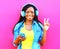 Cool african girl in headphones listens to music over pink