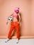 Cool athletic woman with pink hair and stylish visor in bright sportswear is posing with soccer ball under her arm