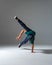 Cool b-boy dancing on one hand in studio  on gray background. Breakdance poster