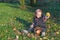 Cool baby boy ishowing fresh apple sitting in autumn garden