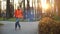 Cool bearded man wearing orange coat and jeans dances on roller skates in autumn in a central city park on a background