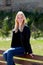 Cool blonde girl sitting on a wooden bench