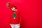 Cool boy with curls on a red background in a sweater with a christmas tree