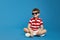 Cool boy in red striped shirt and trendy sunglasses feels happy and looking away at free empty space