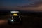 Cool car with illuminated headlights isolated in the field in the evening