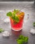 Cool cherry drink with orange and mint in a glass mug with ice cubes