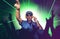 Cool deejay playing music at party event in night club mixing techno songs on laser and flash lights background cheered with hands