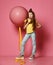 Cool and fashion teen girl in jeans and yellow t-shirt stepped on balloon yellow tape, drinks yellow juice and looks somewhere up