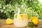 Cool freshly made lemonade in glass pitcher on wooden table