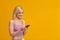 Cool gadget. Excited lady using smartphone, browsing internet or chatting in social networks, yellow background