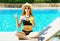 cool girl with cup of juice sitting on deckchair over blue water pool background