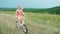 A cool girl in a pink dress rides a bike in the countryside. Carefree childhood in the village. Slow motion 4k video