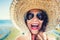 Cool girl, young woman playing with hat on beach on a summer sunny day.