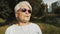 Cool grandmother with pink sunglasses and headphones listening music