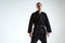 Cool guy in black kimono fighter posing in karate stance on white studio background with copy space