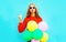 Cool happy girl does an air kiss with colorful balloons