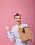 Cool happy man with a cardboard box with pens, plant and different things