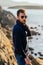 Cool Hispanic male with sunglasses on a rocky coast