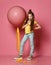 Cool and impudent teen girl in jeans and yellow t-shirt stepped on big pink balloon yellow tape, drinks yellow juice