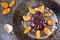 cool jelly with fruits and powder decorated with plums and vintage spoon on a dark plate on black wooden background close up