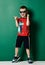 Cool kid boy in blue sunglasses sneakers, shorts and red t-shirt is laughing and pointing his finger at something