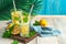 Cool lemonade with ice and mint on a blue background with palm leaves.