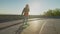 Cool lovely woman skateboarding and chatting on cellphone at sunrise