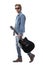 Cool macho rocker male in jeans walking and holding acoustic guitar wearing sunglasses.