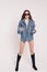 Cool model in denim jacket, gun boots and sunglasses posing