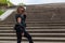 Cool portrait of a woman in black clothes on the steps of a city staircase . Free and independent woman concept