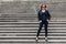 Cool portrait of a woman in black clothes on the steps of a city staircase. Free and independent woman concept