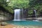 A cool refreshing waterfall pouring into an emerald pond hidden in a mysterious forest of lush greenery