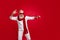 Cool santa character aged man moving like star at exciting party wear sun specs knitted clothes isolated red background