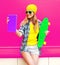 Cool smiling woman taking selfie picture by tablet pc with skateboard wearing colorful yellow hat on pink