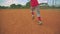 Cool steadicam shot of kid running to first base on baseball field. Shot from behind him