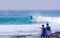 Cool surfer dude carving a beautiful blue barrel wave as friends watch him.