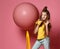 Cool teen girl in jeans and yellow t-shirt stepped on balloon yellow tape, drinks yellow juice and oversee and greets something up