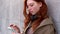 Cool teen redhead girl standing on city urban street using cell phone.