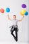 Cool teenage boy holding a bunch of balloons jumps in an empty room