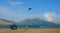 Cool tourist woman kitesurfing past the her SUV and lounge chair on sandy beach.