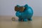 Cool turquoise piggy bank with golden glasses with one euro coin