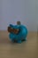 Cool turquoise piggy bank with golden glasses with one euro coin