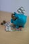 Cool turquoise piggy bank with golden glasses with pills and eur