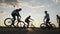 Cool young bikers team doing freestyle front wheelie trick outside with sunset in background -