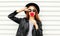 Cool young girl with red lollipop heart wearing fashion black hat leather jacket over white urban